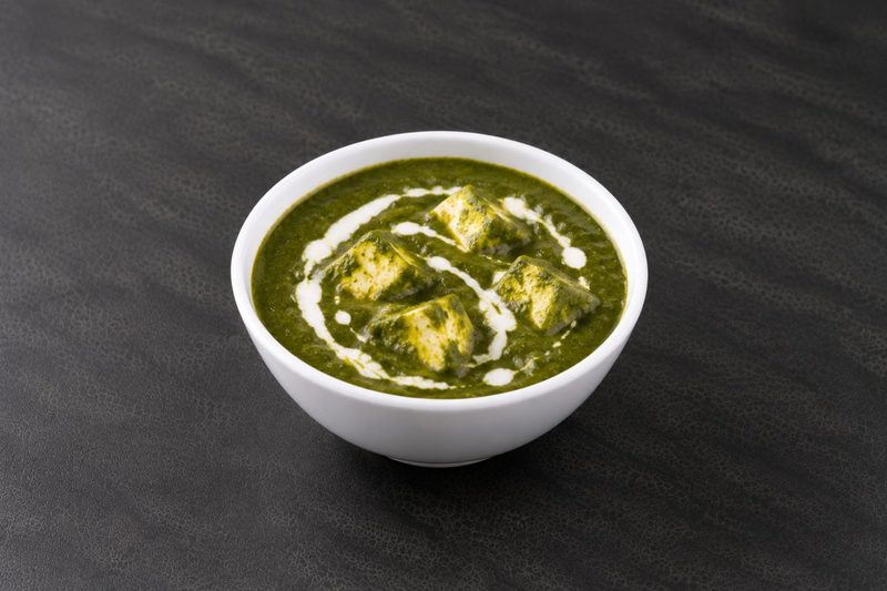 Palak paneer — cubes of paneer in a deep green spinach gravy, finished with a swirl of cream